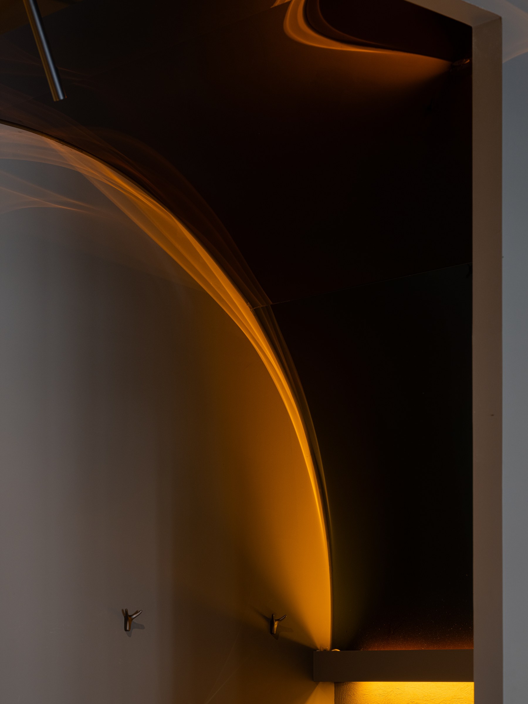Curved detail where amber light meets a dark wall