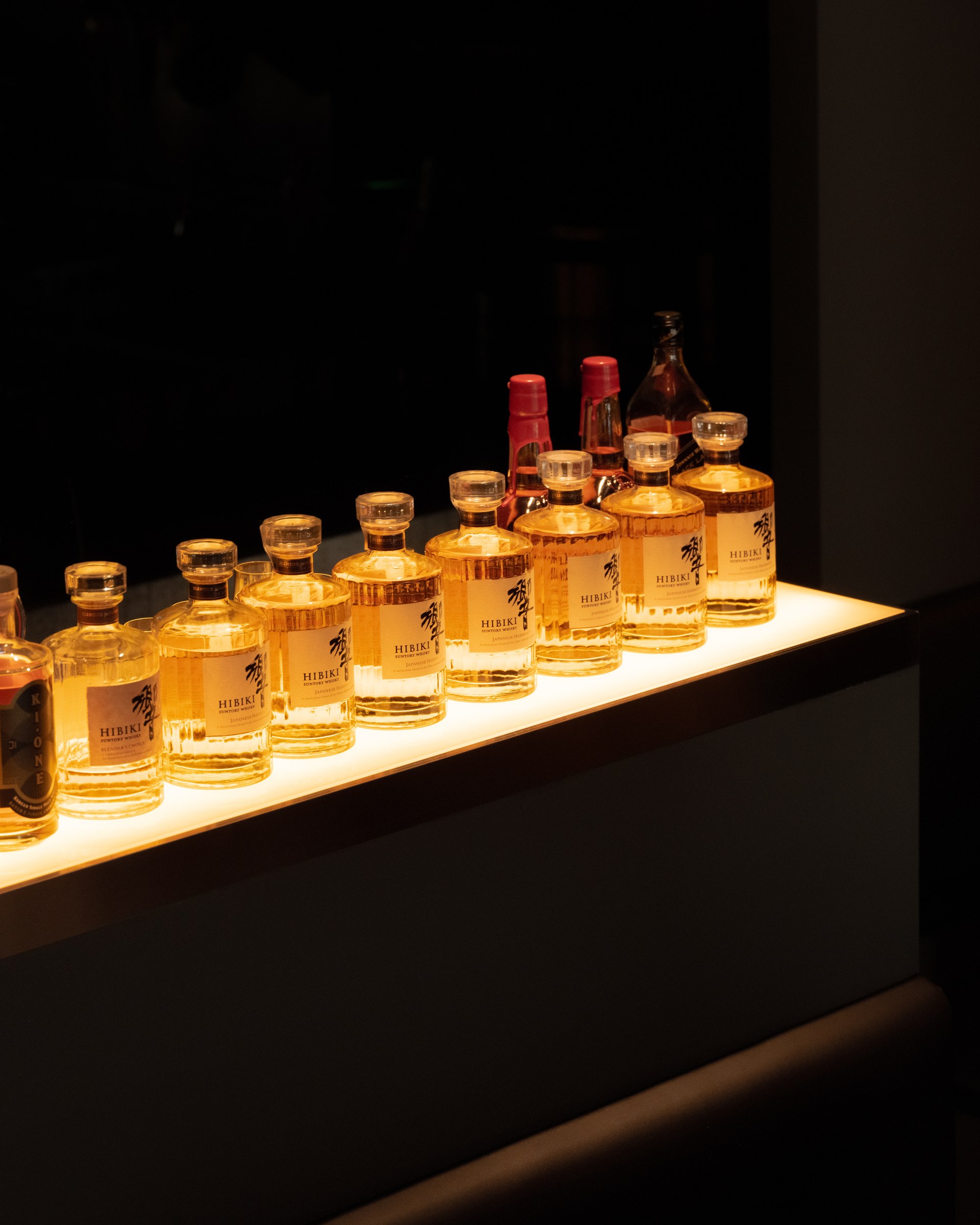 A line of bottles illuminated on the bar shelf