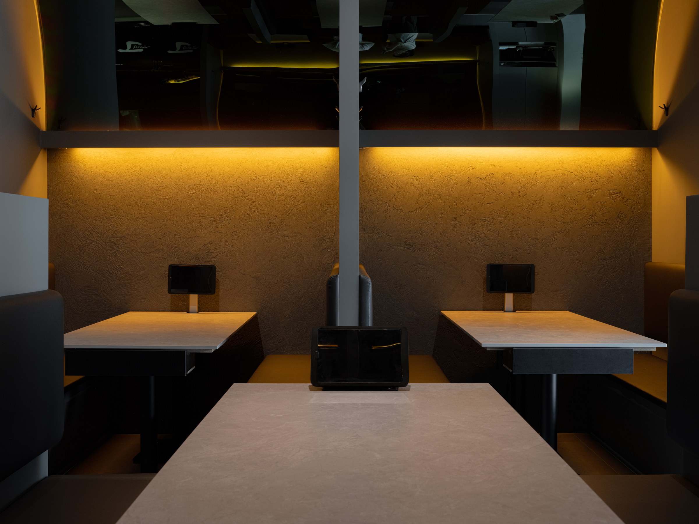 Facing private booths beneath amber concealed lighting