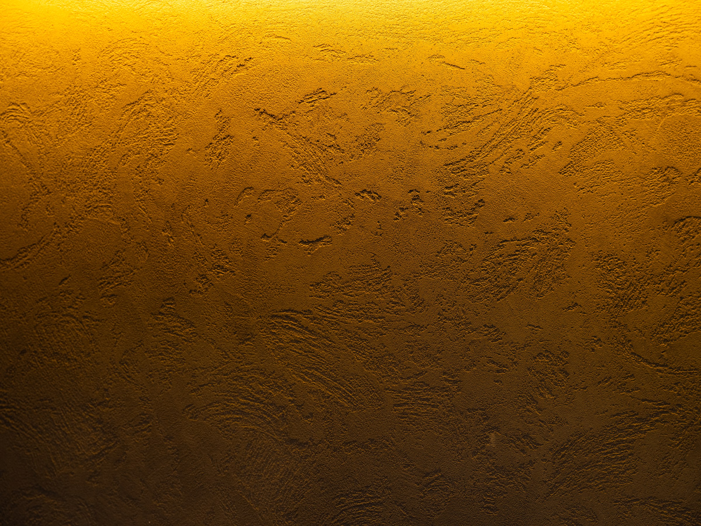 Textured plaster surface revealed by amber light