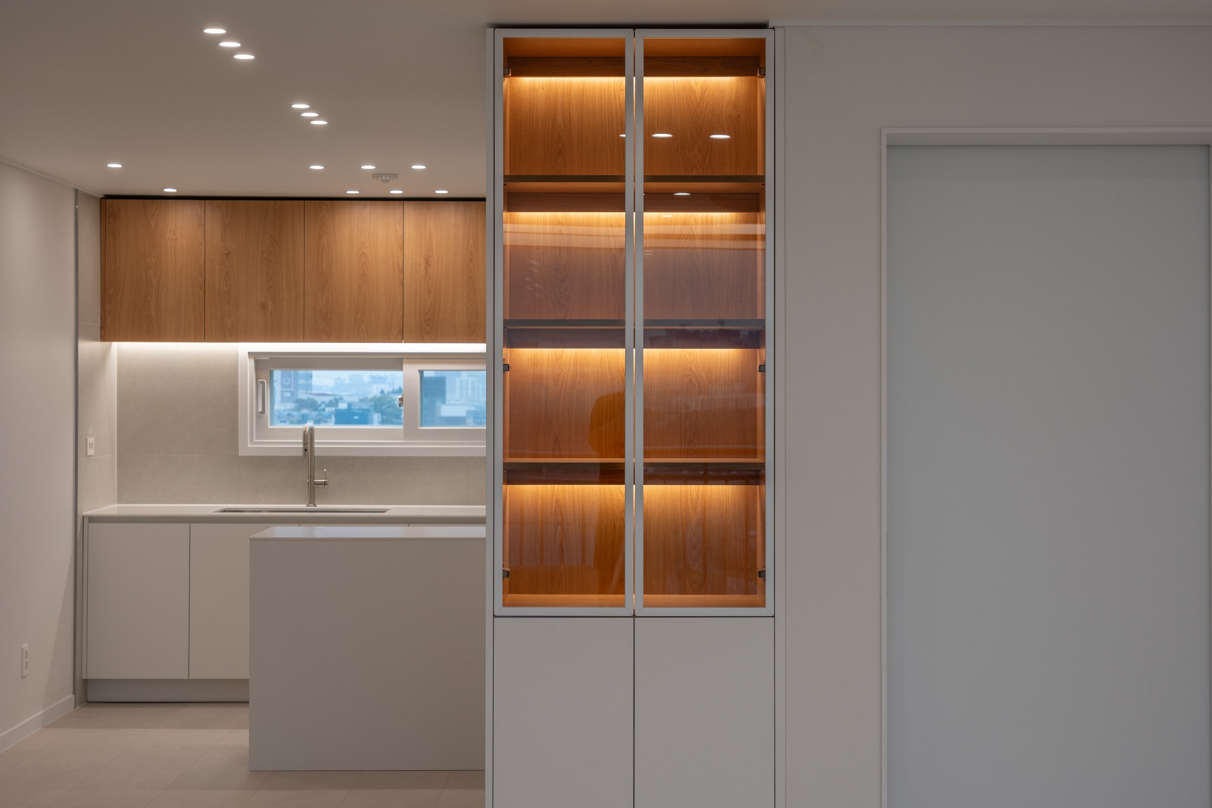 Kitchen accented by a warmly illuminated timber cabinet